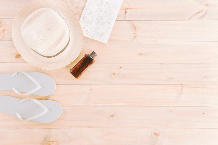 Free Photo hat; map; flip flops and bottle on wooden plank background