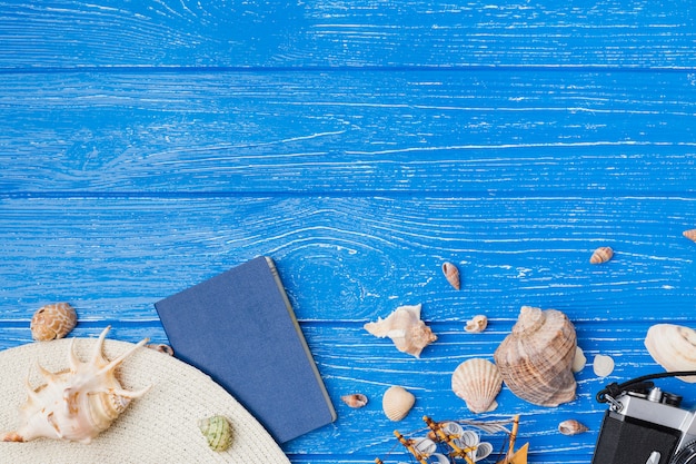 Hat with camera among seashells and toy boat