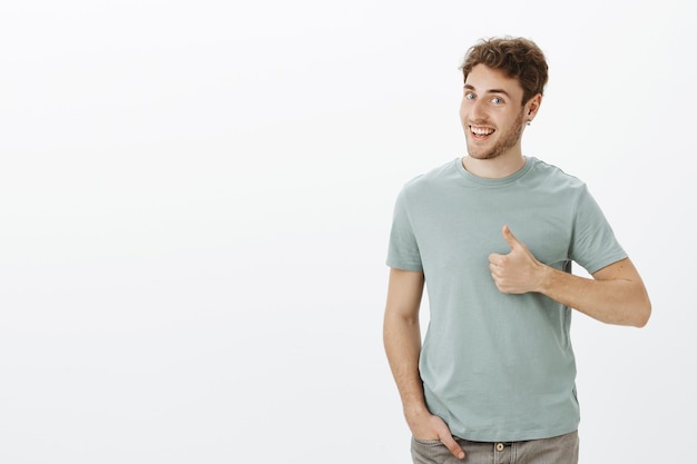 Free photo have not heard ideas better. portrait of positive good-looking male model with bristle in earrings, turning head in profile and smiling broadly while showing thumbs up