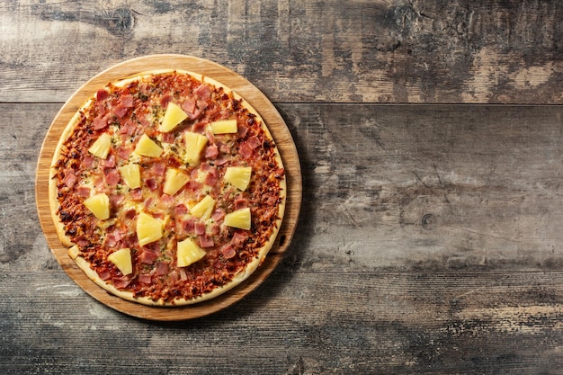 Hawaiian pizza with pineappleham and cheese on wooden table
