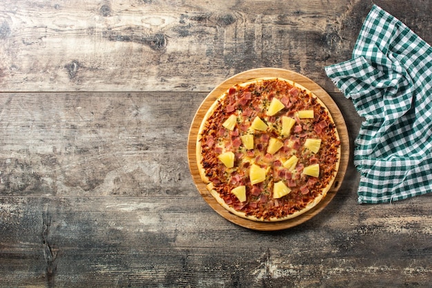 Hawaiian pizza with pineappleham and cheese on wooden table