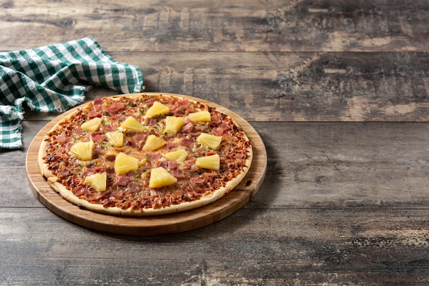 木製のテーブルにパイナップルハムとチーズのハワイアンピザ