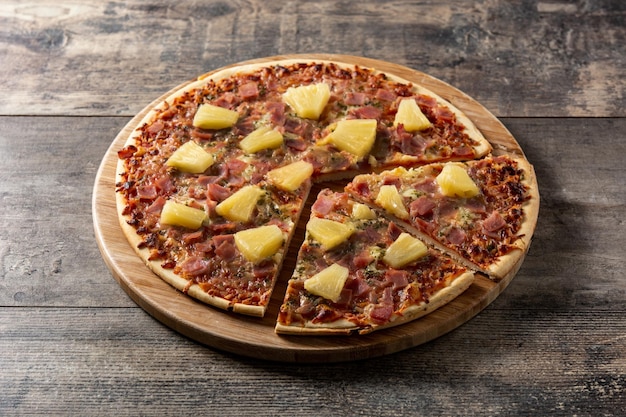 Hawaiian pizza with pineappleham and cheese on wooden table
