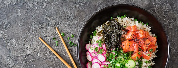 ハワイアンサーモンフィッシュポークボウル、ライス、ラディッシュ、キュウリ、トマト、ゴマ、海藻。仏丼。ダイエット食品。上面図。フラット横たわっていた。