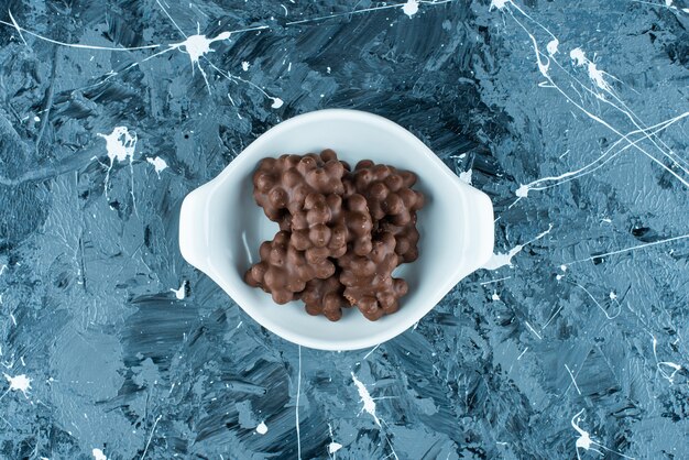 Hazelnut chocolate in a bowl, on the blue table. 