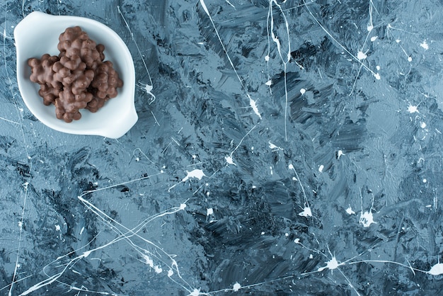 Hazelnut chocolate in a bowl, on the blue table. 