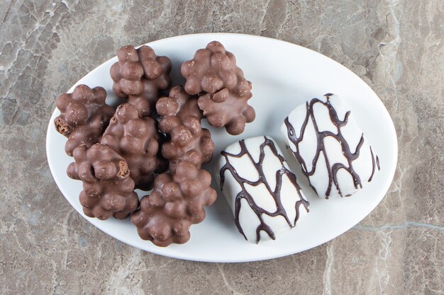 Hazelnut chocolate and candies on a plate on blue.