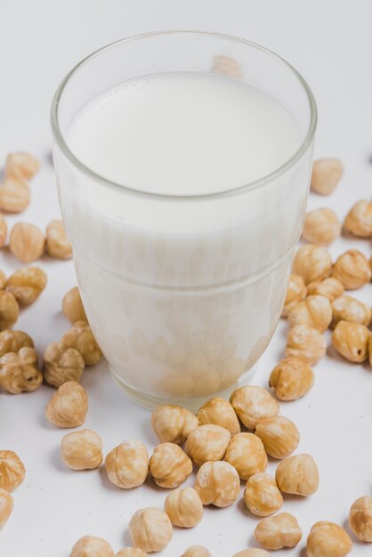 Hazelnuts around glass of milk