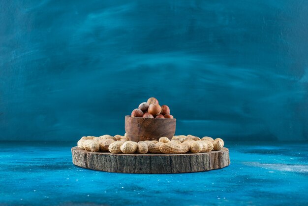 파란색 표면에 땅콩과 보드에 그릇에 헤이즐넛