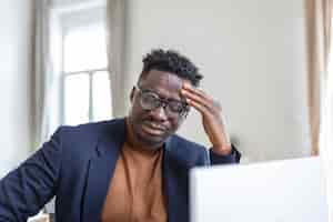 Free photo head shot stressed young african american man touching forehead suffering from terrible headache working on computer at home office frustrated confused biracial guy having painful feelings in head