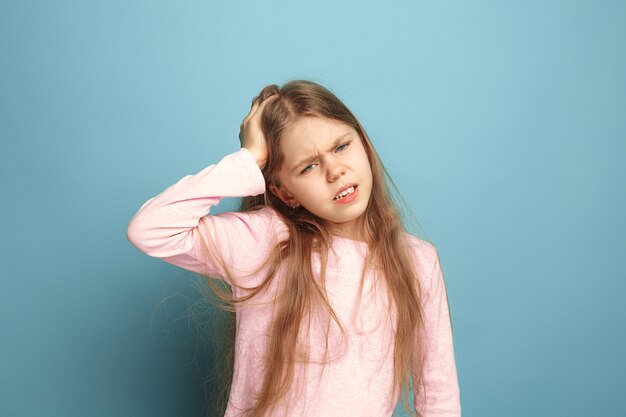 headache. sad teen girl with headache or pain on blue. Facial expressions and people emotions concept