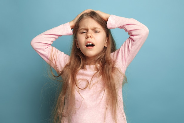 The headache. The sad teen girl with headache or pain on a blue studio background. Facial expressions and people emotions concept. Trendy colors. Front view. Half-length portrait