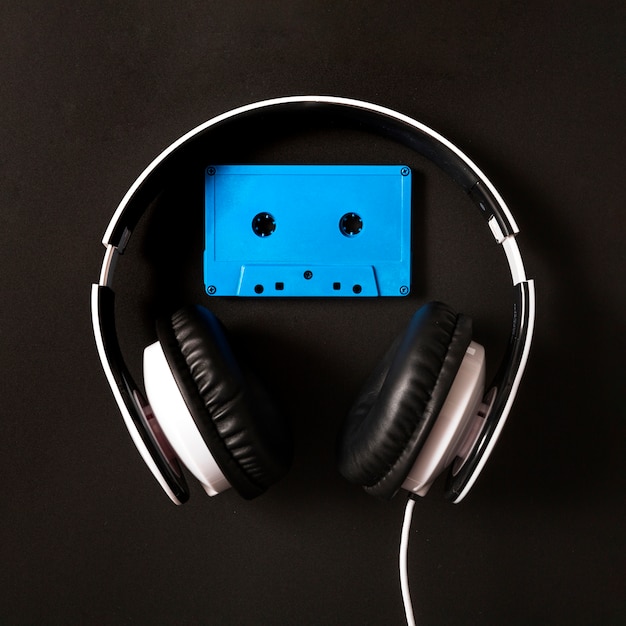 Headphone over the blue cassette tape on black background