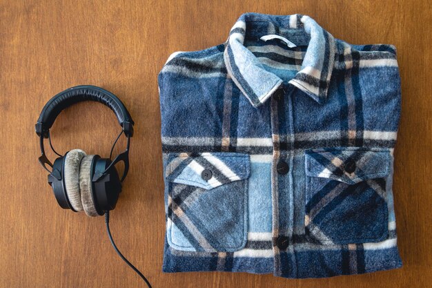 Headphones and a folded plaid shirt on a wooden background