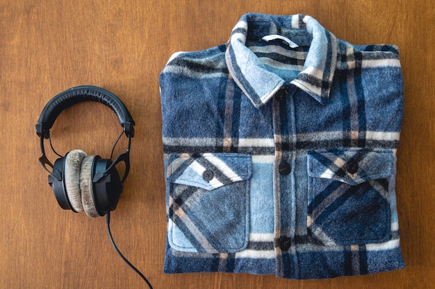 Headphones and a folded plaid shirt on a wooden background