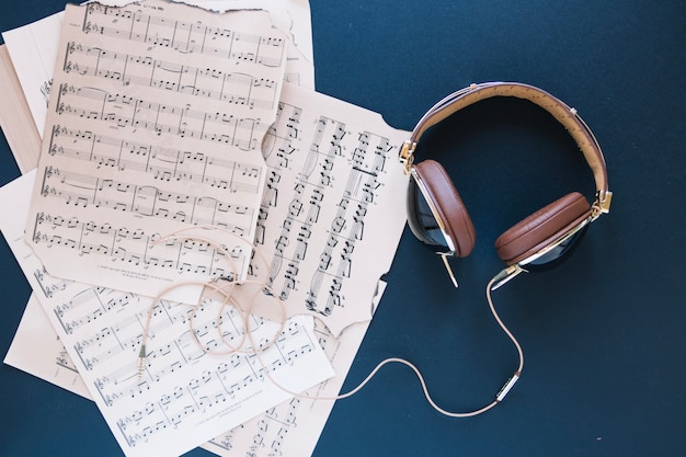 Free photo headphones near pile of sheet music