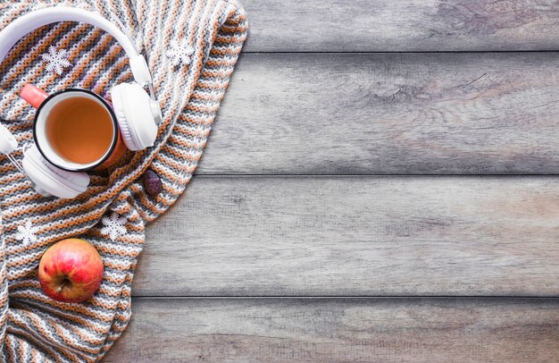 Headphones and tea near apple on blanket