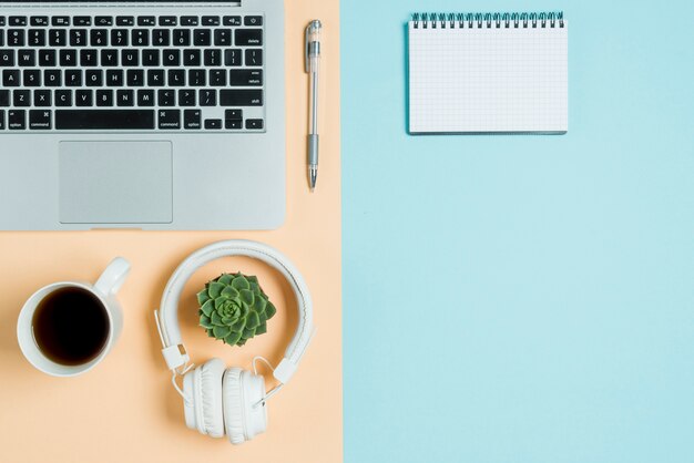 Headphones and tea near laptop and notebook