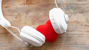 Free photo headphones with red heart on wooden table