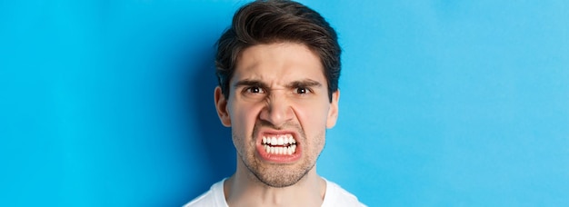 Foto gratuita colpo alla testa di un uomo caucasico arrabbiato che guarda con disprezzo e sgomento essendo arrabbiato con la persona in piedi contro b