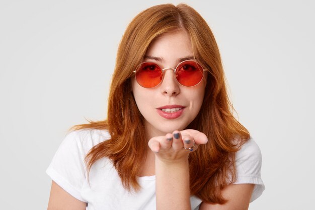 Headshot of coquette ginger female blows kiss at camera