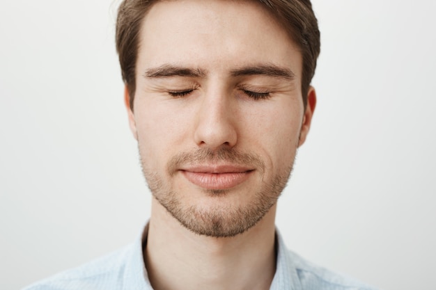 Headshot of cute adult bearded man close eyes and smiling