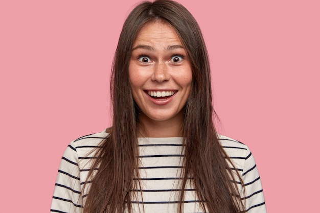 Headshot of excited brunette European woman with surprised positive expression