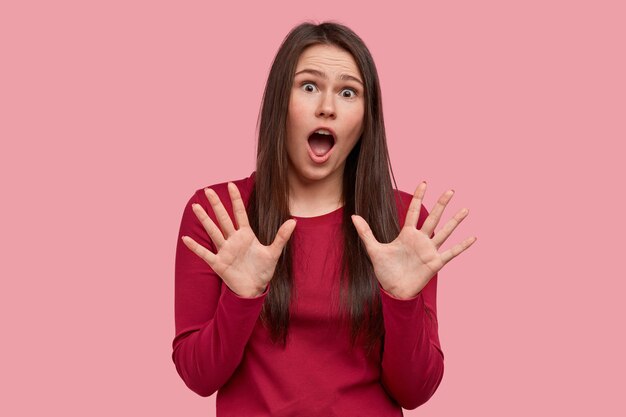 Headshot of frightened Asian lady shows palms in protective gesture, afraids of phobia, keeps mouth opened