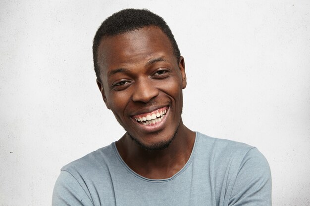 Headshot of handsome emotional young Afro-American man with cheerful happy smile