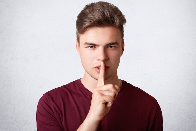 Headshot of handsome hipster guy looks secretly at camera