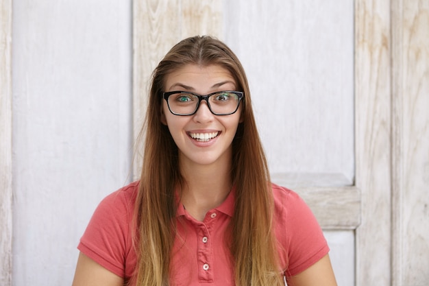 Foto gratuita primo piano del volto della giovane donna felice ed eccitata che indossa occhiali da sole rettangolari alla ricerca, alzando le sopracciglia per lo stupore