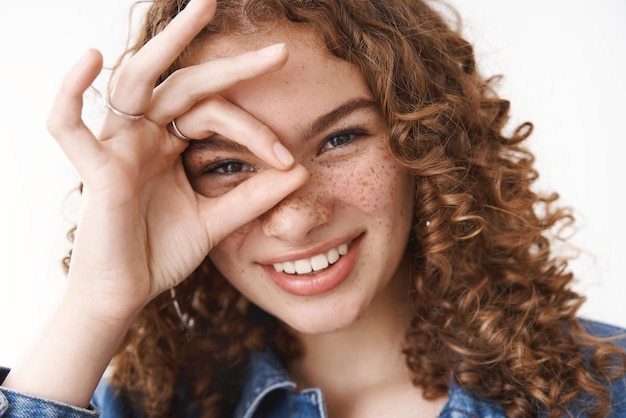 Headshot happy lucky positive young girl show okay ok sign around eye smiling joyfully having fun awesome day standing positive expressing approval agree optimistic mood standing white background