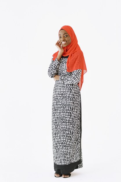 Headshot of lovely satisfied religious Muslim woman with gentle smile, dark healthy skin, wears scarf on head. Isolated over white background.