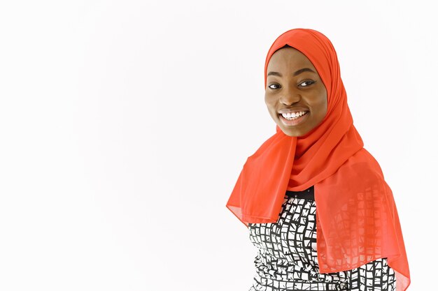 Headshot of lovely satisfied religious Muslim woman with gentle smile, dark healthy skin, wears scarf on head. Isolated over white background.