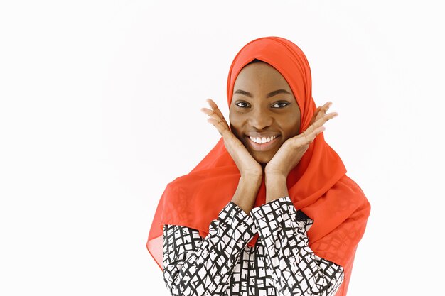 穏やかな笑顔、暗い健康な肌、頭にスカーフをかぶった素敵な満足した宗教的なイスラム教徒の女性のヘッドショット。白い背景に分離されました。