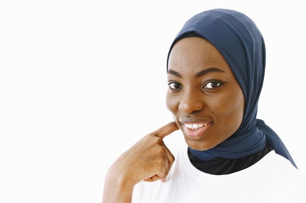 Headshot of lovely satisfied religious Muslim woman with gentle smile, dark healthy skin, wears scarf on head. Isolated over white background.