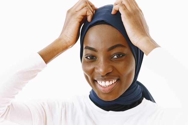 Headshot of lovely satisfied religious Muslim woman with gentle smile, dark healthy skin, wears scarf on head. Isolated over white background.