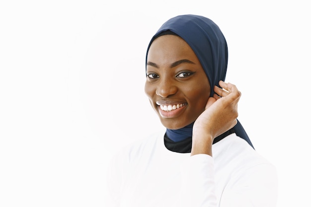 Headshot of lovely satisfied religious Muslim woman with gentle smile, dark healthy skin, wears scarf on head. Isolated over white background.