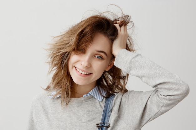 Headshot of lucky young lady touching her head with hand  with broad smile. Good-looking housewife being surprised after winning in lottery. Unexpectedness, rejoice