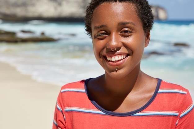 Free photo headshot of pleasant looking cheerful black young woman with boyish appearance