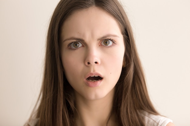 Headshot portrait of astonished young woman