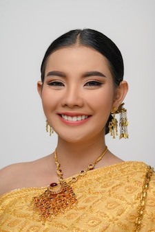 Headshot, portrait beautiful asian woman in traditional thai dress costume smile and pose gracefully on white wall