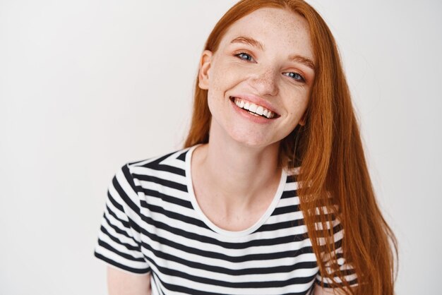 Headshot Portrait of happy ginger girl with freckles smiling looking at camera White background