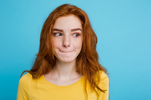 Headshot Портрет счастливый рыжий рыжий волосы девушка с веснушками, улыбаясь, глядя на камеру. Пастель синий фон. Копирование пространства.