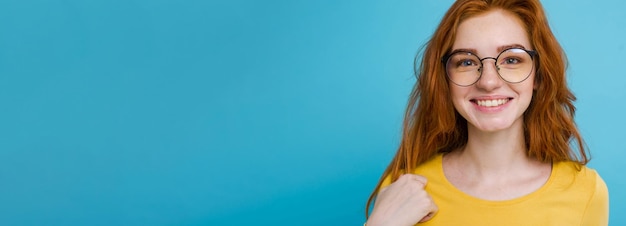 Foto gratuita ritratto in primo piano della ragazza felice dei capelli rossi dello zenzero con le lentiggini che sorride guardando la fotocamera blu pastello