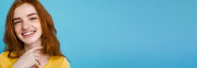 カメラ パステル ブルーを見て笑っているそばかすのある幸せな生姜赤い髪の少女のヘッド ショットの肖像画