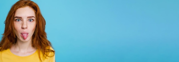 Portrait of a Happy Red-Haired Girl with a Funny Expression on Pastel Blue Background