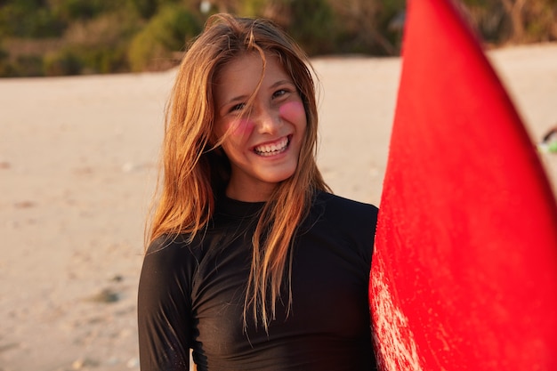 Foto gratuita headshot di surfista caucasico positivo in muta nera, ha un sorriso a trentadue denti sul viso