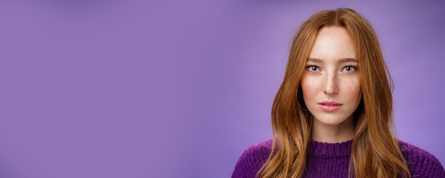 Headshot of sensual and attractive tender redhead female with freckles and pure skin looking at came