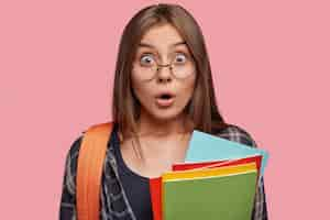 Free photo headshot of stunned student posing against the pink wall with glasses